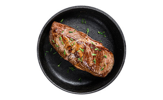 Grilled veal fillet meat steak in a pan with herbs. Isolated on white background