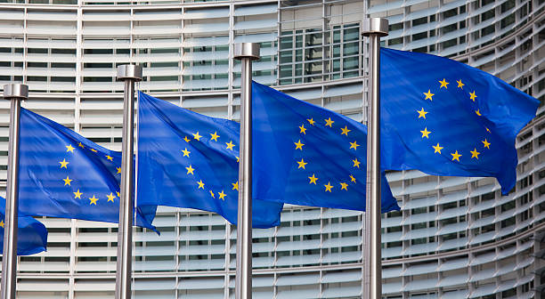 Row of European Union flags waving in the wind European flags in front of the Berlaymont building, headquarters of the European commission in Brussels. european union flag photos stock pictures, royalty-free photos & images
