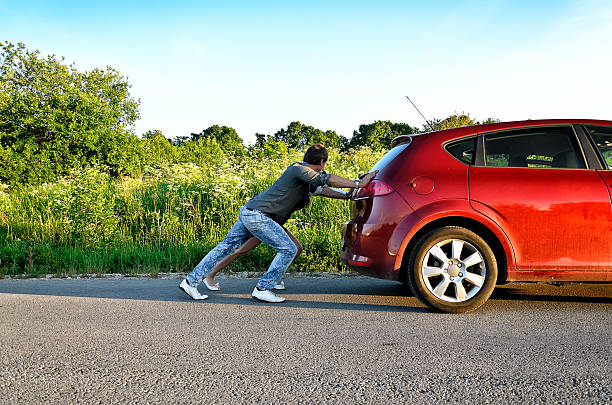 istock Man and woman pushing a broken car 177434042