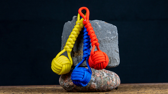 Braided paracord keychain on a background of stones. Handmade, creative design.