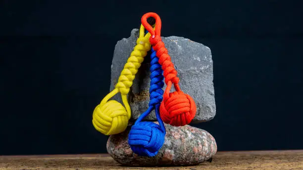 Photo of Braided paracord keychain on a background of stones. Handmade, creative design.