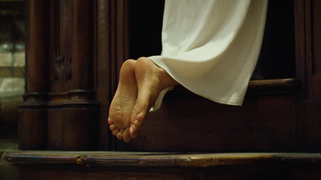 Barefoot pilgrim tramp praying in church. Confession of sins to a priest. The woman came to the priest to repent. Repentance for sins.