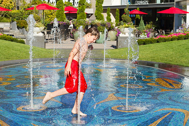 Boy running through water in fountain stock photo