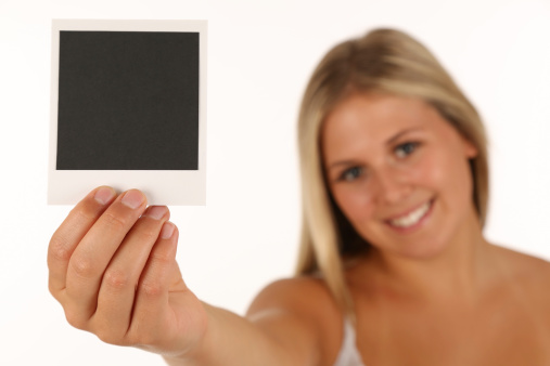 Beautiful young blonde woman holding a blank polaroid