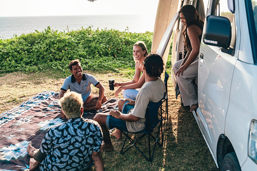 A group of multiracial young people enjoying camper van time on the beach in Bali, Indonesia