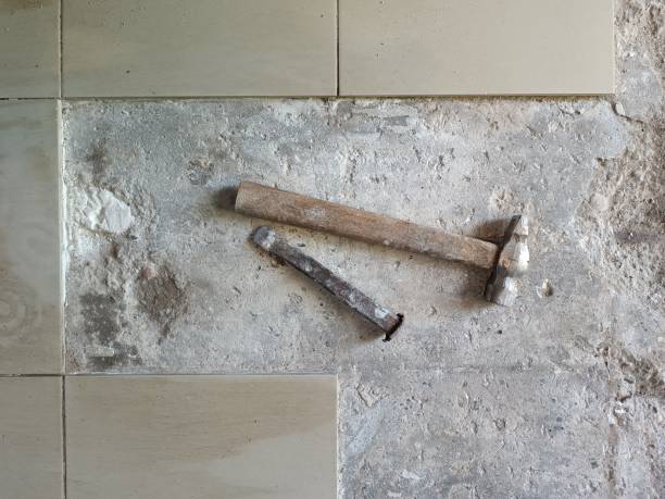 Floor tile removal. Old tools on floor. Dismantling old floor tiles. Renovations.Chisel and hammer on concrete slab. Very old construction tools. Preparing for repair work. Flooring restoration eliminación de baldosas. herramientas viejas en el suelo. desmontaje de baldosas viejas. reformas.cincel y martillo sobre losa de hormigón. herramientas de construcción muy antiguas. preparación para trabajos de reparación. restauración de pavimentos