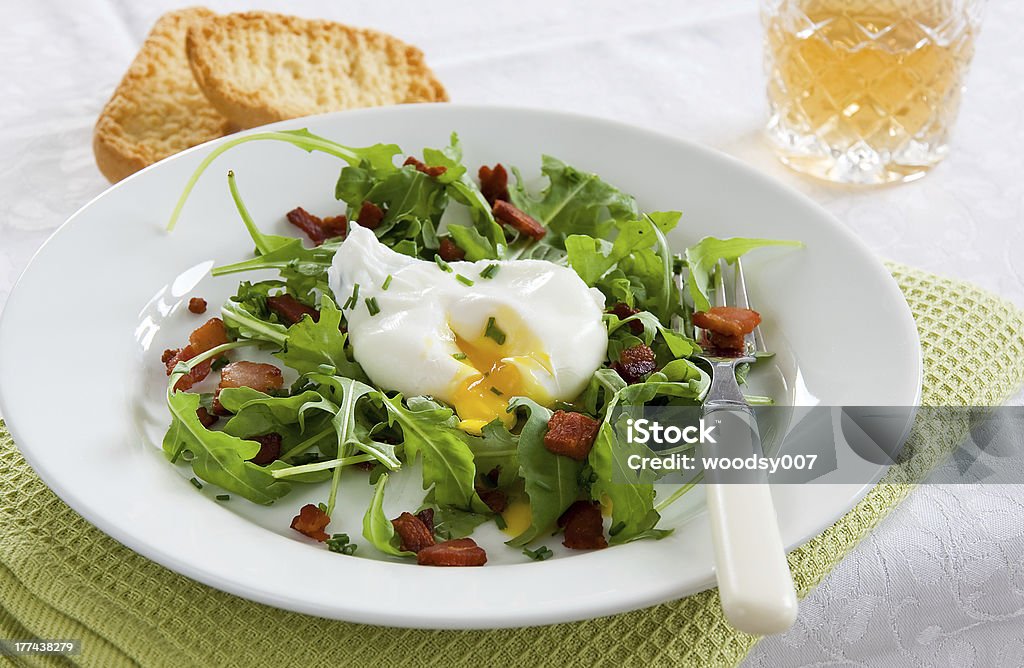 French Bistro Salad A green French bistro style salad with poached egg and chives on a white plate and table setting Appetizer Stock Photo