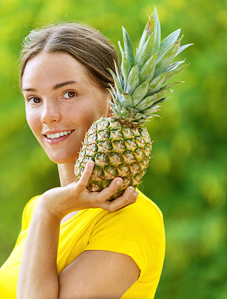 young woman in yellow blouse with pineapple stock photo
