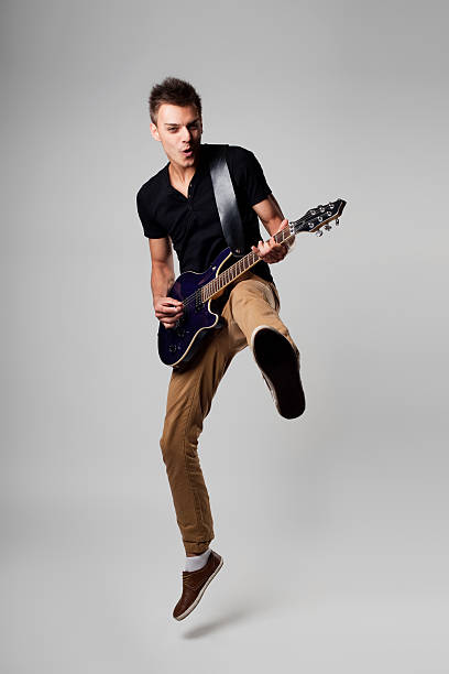 Rockstar leap with guitar Rockstar men jumping with guitar while playing guitarist stock pictures, royalty-free photos & images