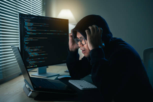 istock Hacker man wearing glasses and hood depression or serious mistake for hack network security system. Dangerous Hooded Hacker Breaks into Government Data Servers and Infects Their System with a Virus. 1774414620