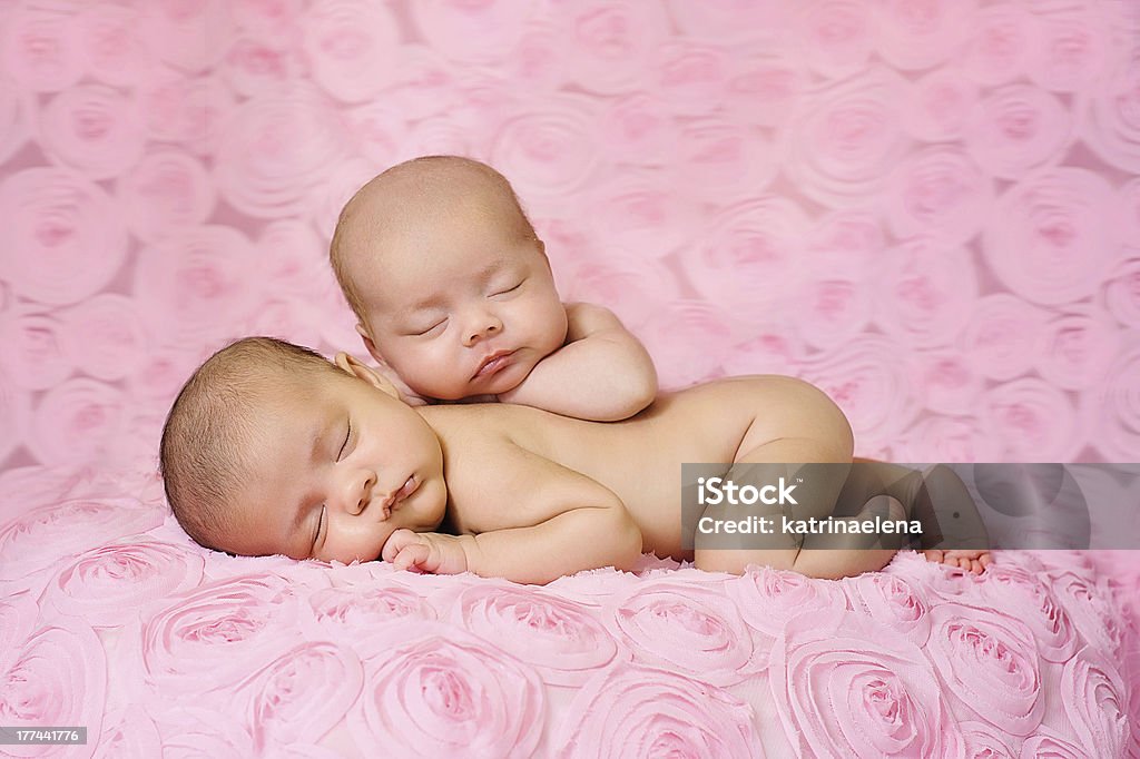 Bliźniaki dwujajowe newborn baby dziewczyny spania na pink rose tkanina - Zbiór zdjęć royalty-free (Bliźniaki)