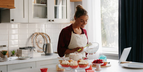 istock Smiling female pastry chef applying whipped cream while making a cake at the domestic kitchen 1774421059