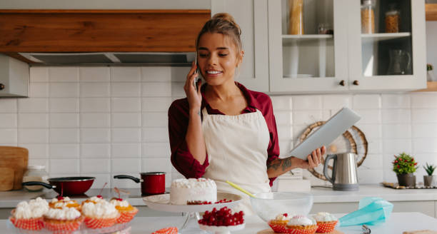 istock Confident female confectioner discussing order details while talking on phone with client at the kitchen 1774423967