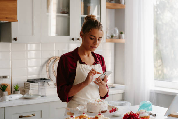 istock Confident young female pastry chef using smart phone while making a cake at the domestic kitchen 1774423974