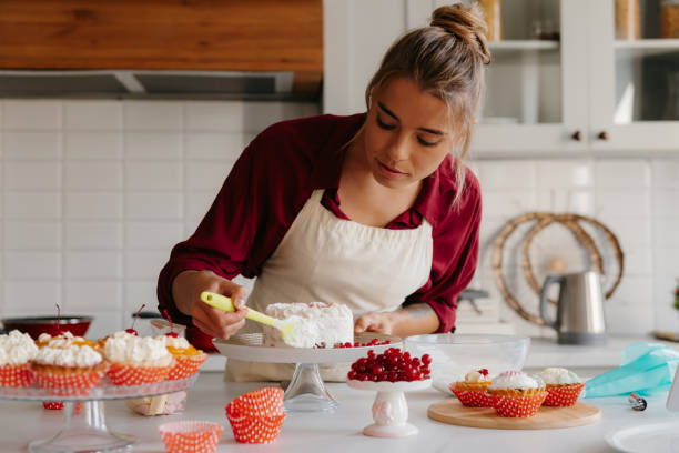 istock Concentrated female pastry chef applying whipped cream while making a cake at the domestic kitchen 1774424007