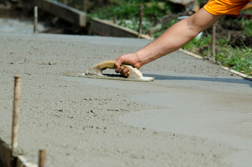 Man smoothing concrete with a hand trowel.