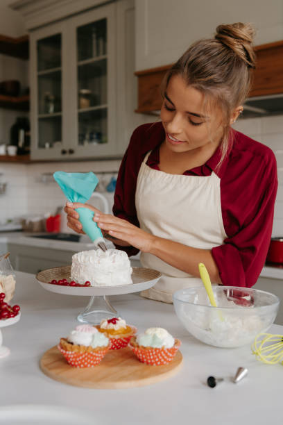 istock Confident female pastry chef applying whipped cream while decorating cake at the kitchen 1774425205