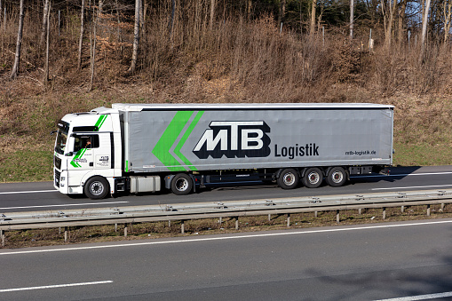Wiehl, Germany - March 24, 2021: MTB Logistic MAN TGX truck with curtainside trailer on motorway