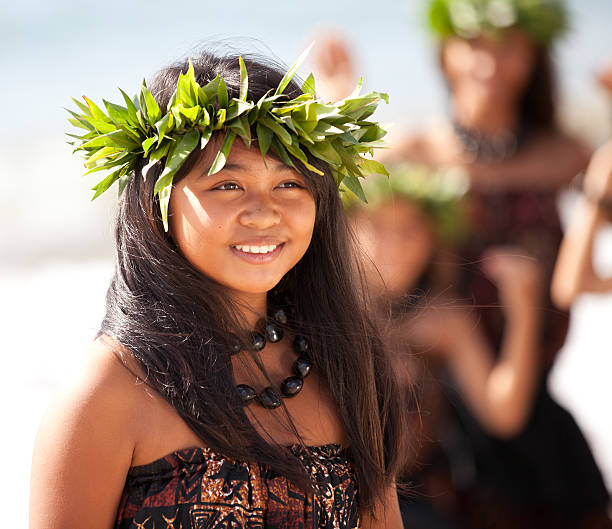 Pretty Polynesian Girl Hula girl on the beach with her fellow dancers behind her hula dancing stock pictures, royalty-free photos & images