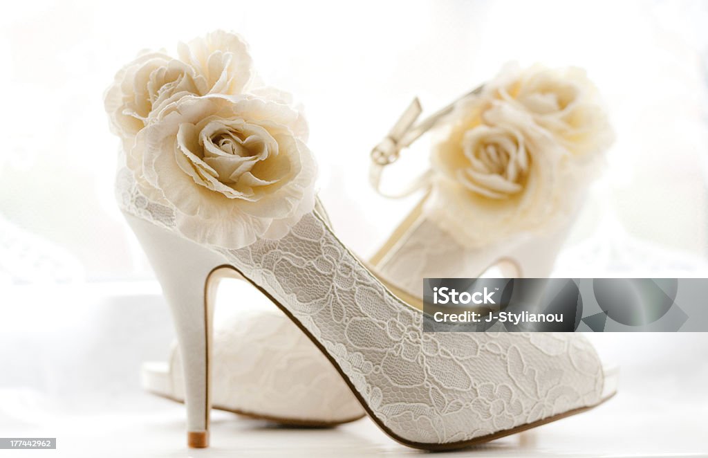 Close up of stylish bridal shoes covered with lace and roses Detailed bridal wedding shoes. Adult Stock Photo