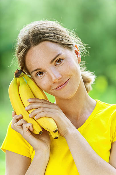 young woman in yellow blouse with banana stock photo