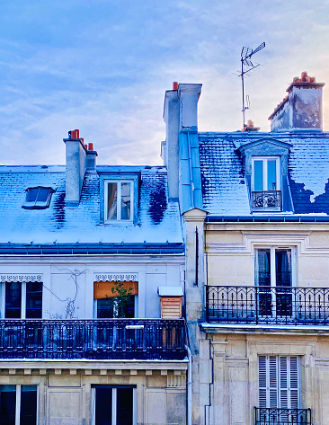 Paris roofs in the snow with a bluish atmosphere, creating a calm and enchanting ambience.