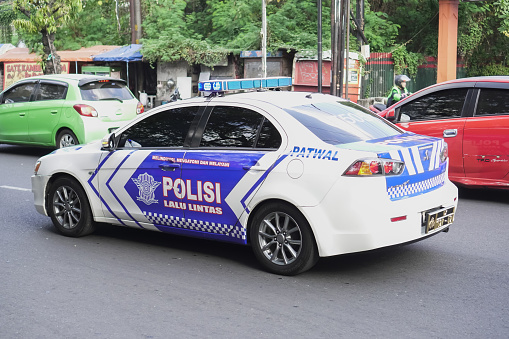 Yogyakarta, Indonesia - August 5, 2023: Indonesian police patrol car on the crowded road seen from the side daylight during the day. Police on duty.