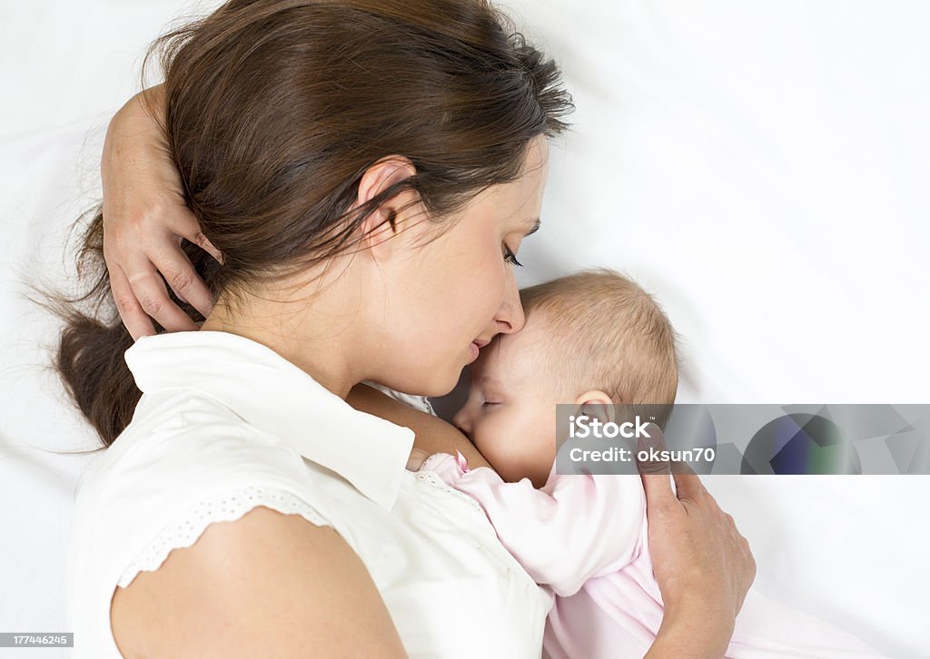 Mother breastfeeding infant daughter while lying down happy mother breast feeding her baby infant Breastfeeding Stock Photo
