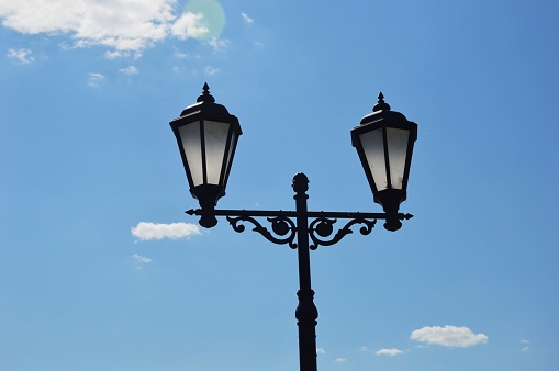 Black street glass lanterns against a blue sky. City lighting.