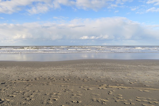 It's low tide on the beach of Schiermonnikoog. The clouds are reflected on the wet wadden sea.