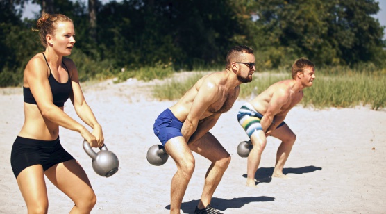 Group doing gym workout on beach on a hot summer day