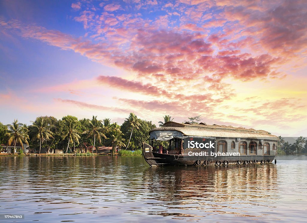 House boat in backwaters House boat in backwaters near palms at dramatic sunset sky in alappuzha, Kerala, India Kerala Stock Photo