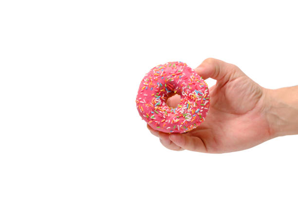 istock Donut with pink icing and multicolored sugar sprinkles in your hand, white background. 1774487173