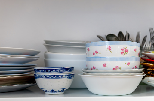 Tableware and dinnerware on a kitchen shelf.