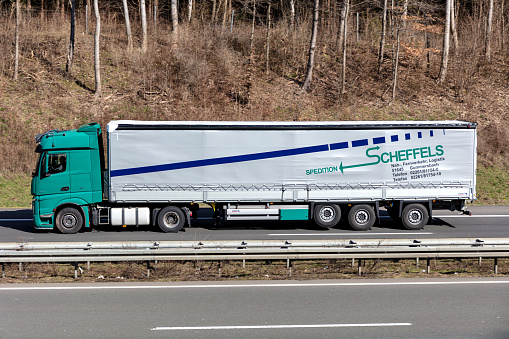 Wiehl, Germany - March 24, 2021: Spedition Scheffels Mercedes-Benz Actros truck with tarpaulin trailer on motorway
