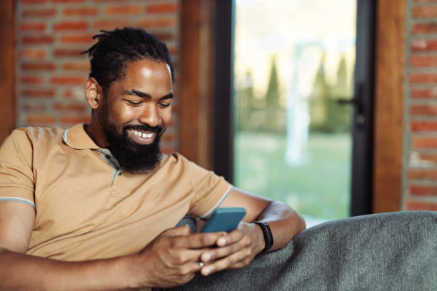istock Young happy black man reading a text message on cell phone at home 1774542120