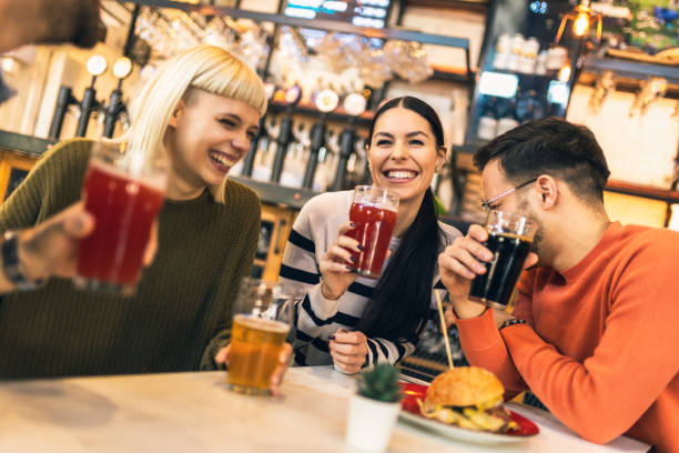 istock Smiling young friends drinking craft beer in pub 1774542578