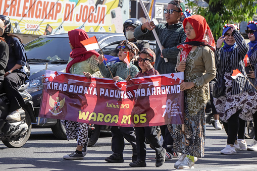 Yogyakarta, Indonesia - August 16, 2023: People wear traditional clothes marching on highway. The troupe parades in the carnival celebrate the independence day of Republic of Indonesia on August 17