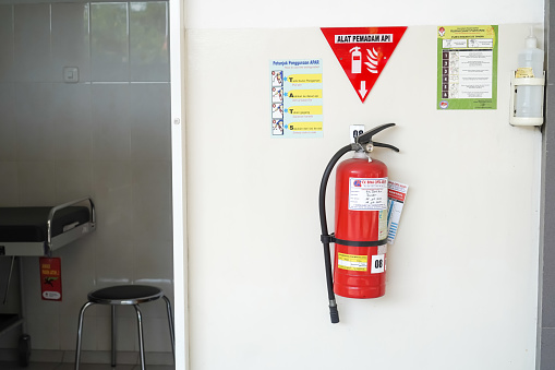 Yogyakarta, Indonesia - August 21, 2023: APAR - Red tank of fire extinguisher system attached on hospital wall. Concept for Hydrant, office, hotel, hospital, mall, factory and industrial buildings.