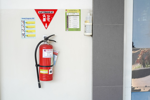 Yogyakarta, Indonesia - August 21, 2023: APAR - Red tank of fire extinguisher system attached on hospital wall. Concept for Hydrant, office, hotel, hospital, mall, factory and industrial buildings.