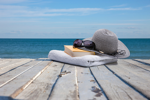 Book, towel, sunglasses and sun hat on the beach