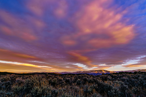 Sawatch Mountain Range Sunset with Clouds - Wide angle view of wispy clouds with dramatic alpenglow light on high mountain peaks. Captured at golden hour just before sunset.
