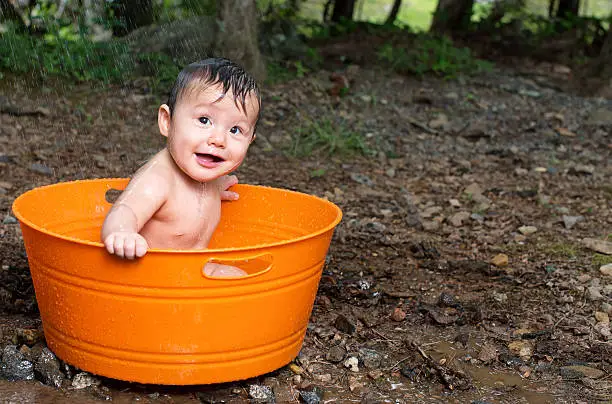 Baby Boy in colorful tub taking a shower out doors.