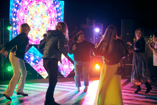 drôles de gens dansant la nuit sur la piste de danse en plein air avec fond de projecteurs multicolores - indian culture dancing dancer women photos et images de collection