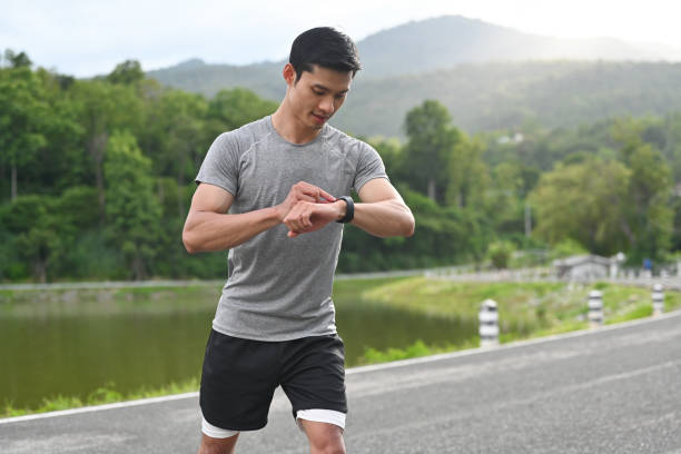 Young Asian athlete man using smartwatch to monitor his activity and progress and track good habits. Young Asian athlete man using smartwatch to monitor his activity and progress and track good habits. asian brisk walking stock pictures, royalty-free photos & images