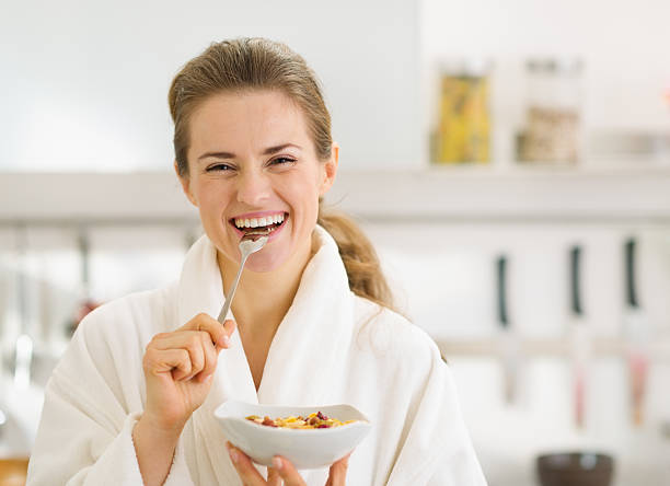 istock Smiling young woman in bathrobe eating healthy breakfast 177458759