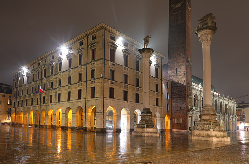 Vicenza, VI, Italy - January 15, 2023: view of Palace of Town Hall called MUNICIPIO in main square while rain with reflections of lights by night