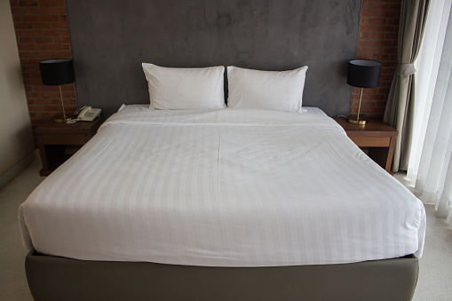 White comfortable pillow on white bed decoration interior of hotel bedroom.