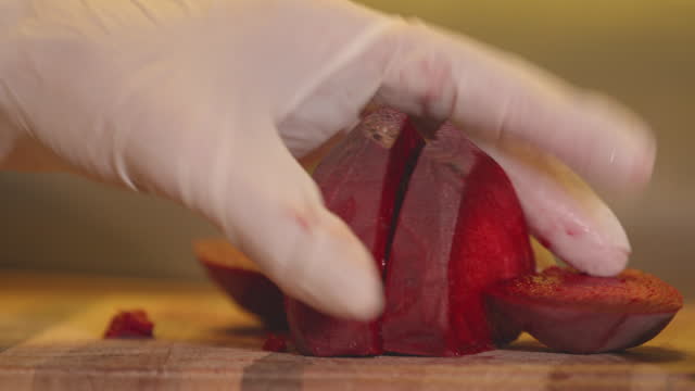 A woman in gloves on her hands cuts beetroot