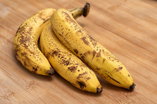 Trzy dojrzałe banany na drewnianej desce do krojenia – zdjęcie